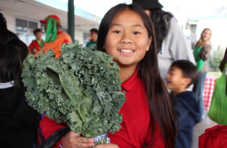 student holding a kale bunch during kids farmers market