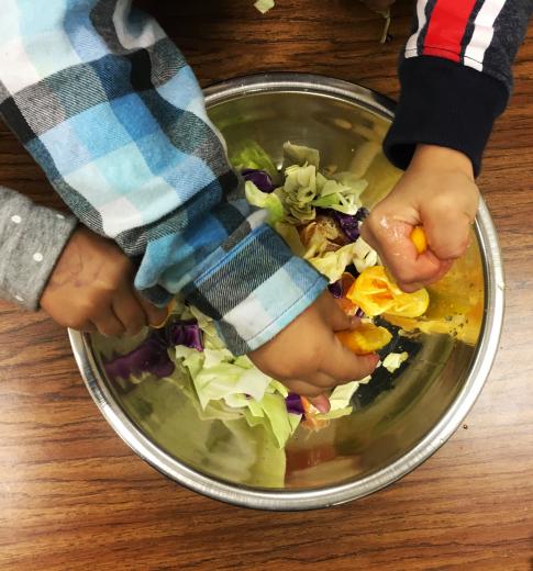Kids squeezing oranges on salad