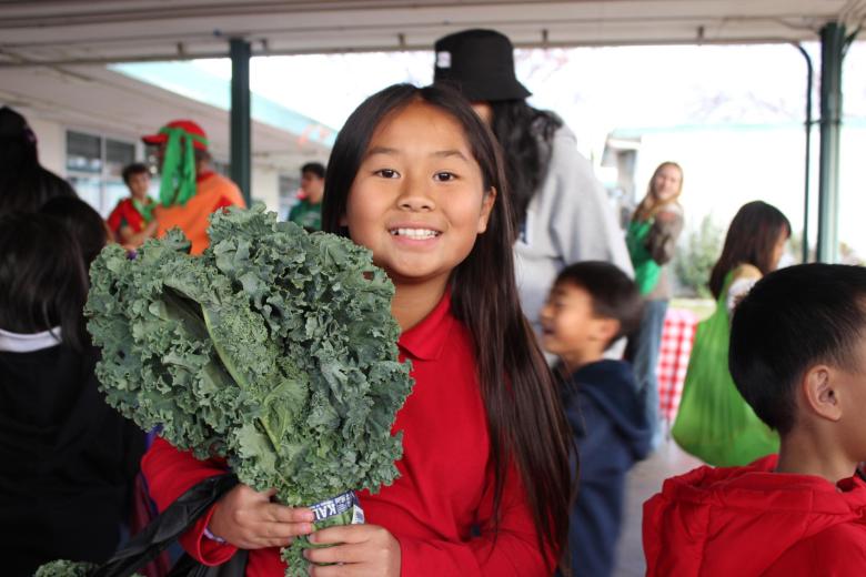 student holding a kale bunch during kids farmers market