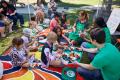Students sitting on grass at farmers market sampling produce 